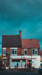 Quaint brick building with exchange office facade under a dramatic sky. Casas Financiadas.