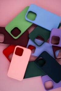 Colorful silicone phone cases laid out on a pastel pink surface, showcasing modern design. Capas de Silicone.