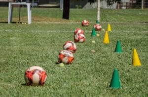 Soccer training equipment arranged on grass in Brasília, Brazil, featuring balls and cones. Bolas de Futebol.