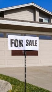 A modern suburban house with a prominent 'For Sale' sign in the front yard, ideal for real estate listings. comprar casa
