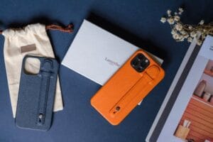 Elegant leather phone cases displayed with accessories on a dark table. Capas Protetoras vs. Capinhas de Celular.