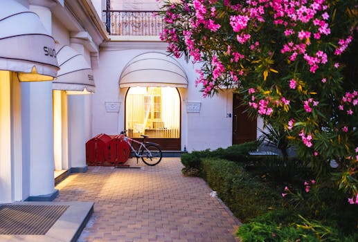 Serene evening view of a boutique hotel entrance in Sochi, adorned with vibrant flowers and warm lighting. Jardim vertical.