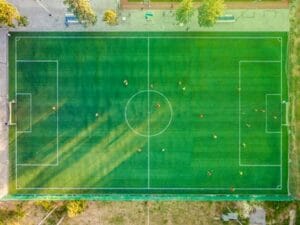 Aerial shot of a soccer game with players on a vibrant green field. Soccer, Futebol.