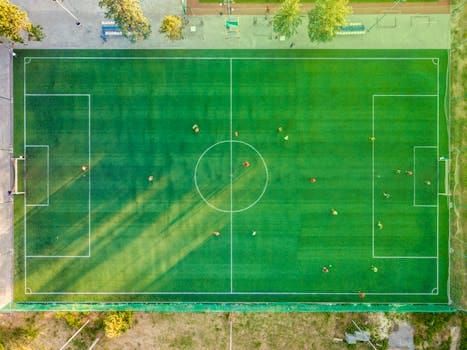 Aerial shot of a soccer game with players on a vibrant green field. Soccer, Futebol.