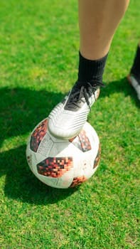 Close-up of a soccer player's foot on a ball on a lush green grass field. Football boot, Chuteira. 