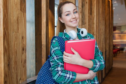 Smiling student holding book and wearing headphones, ready for study. Education, Educação.
