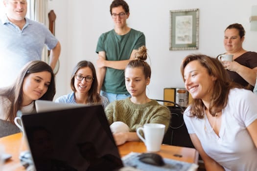 A diverse group of adults at work, enjoying a casual meeting indoors with focus and smiles. Education, Educação.