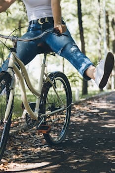 A woman enjoys a relaxing bike ride through a sunlit park path. Cycling, Ciclismo.
