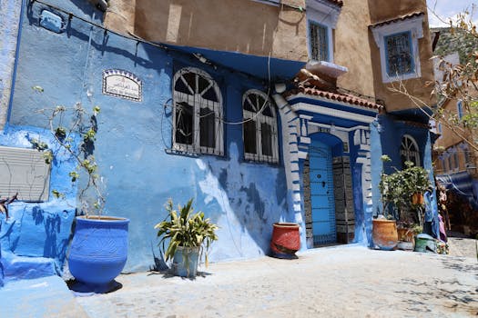 Vibrant blue facade of a building in Chefchaouen, Morocco, adorned with plants and traditional decor. casa.