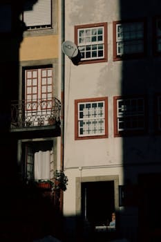 Urban street scene in Porto with sunlight casting dramatic shadows on a residential building. casa.