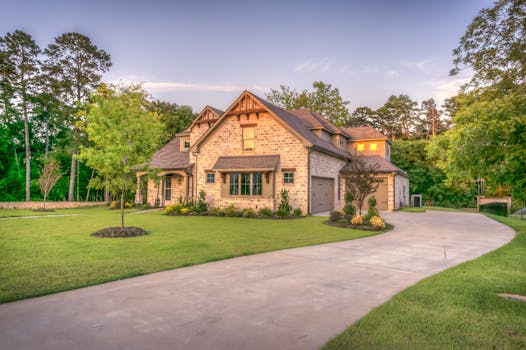 Elegant stone family home surrounded by trees, lush lawn, and vibrant garden. Casa Própria