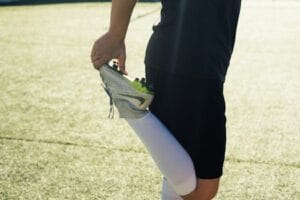 Athlete stretching before soccer practice on a sunny day outdoors. Football boot, Chuteira.