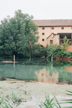 A tranquil scene of an abandoned building reflecting on a calm river in Casier, Veneto, Italy. casa.