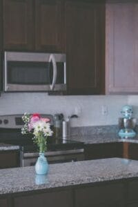 Stylish kitchen interior featuring granite countertops, dark wood cabinets, and a floral vase centerpiece. Kitchen, cozinha.