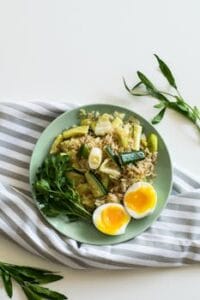 A top view of a healthy vegetable rice dish with soft-boiled eggs on a light green plate. Food, comida.
