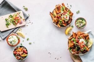 Colorful flat lay featuring sweet potato fries, guacamole, and fresh veggies, perfect for a healthy meal. Food, comida.