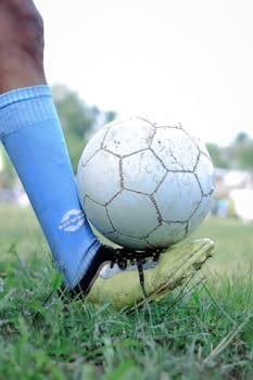 Close-up of a soccer player controlling the ball during a game in Kuttanad. Football boot, Chuteiras.