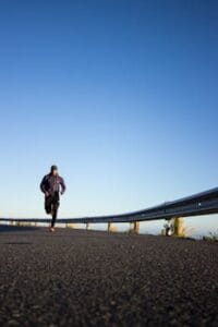 An athletic man jogging on an open road with a clear blue sky in Cape Town, South Africa. Health, Saúde.