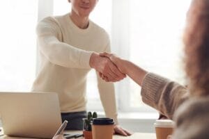 Close-up of professionals shaking hands over coffee in a modern office. Jobs, empregos.