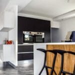 A contemporary kitchen featuring sleek cabinetry and elegant bar stools in a minimalist design. Kitchen, Cozinha.