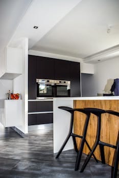 A contemporary kitchen featuring sleek cabinetry and elegant bar stools in a minimalist design. Kitchen, Cozinha.