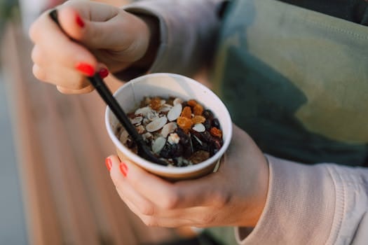 Close-up of hands holding a vegan breakfast bowl with nuts and berries, perfect for a healthy start. Vitamins and Minerals. Vitaminas e Minerais.