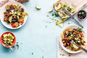 Colorful Mexican salad with avocado, black beans, and lime on a light blue surface. Food, comida.
