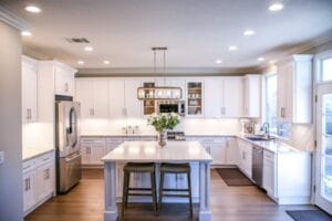 Spacious and elegant kitchen featuring white cabinetry, island, and stainless steel appliances. Modern Kitchen, cozinha, food.