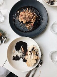 Top view of gourmet dessert plates featuring crumble and a chocolate dish, elegantly plated on a white table. Food, comida, chocolate.