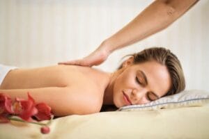 A serene spa scene featuring a woman receiving a therapeutic massage, surrounded by soothing elements. Massage. 