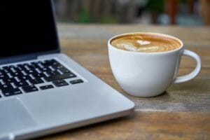 Close-up of a latte coffee with heart art next to a laptop on a rustic wooden table. Caffeine food, comida. food. café.