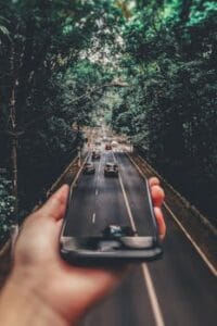 Creative blend of technology and nature with smartphone framing a bustling road through forest. Technology, Tecnologia.