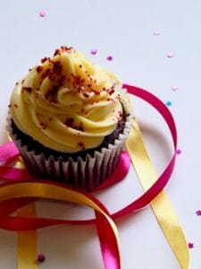 Tempting chocolate cupcake with creamy icing, adorned with colorful ribbons and confetti for a festive celebration. chocolate food, food, comida.